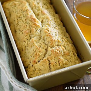rosemary beer bread in loaf pan with glass of beer