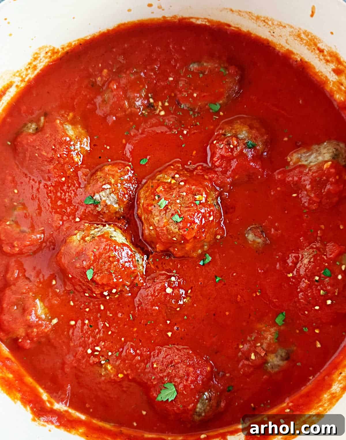 Delicious baked Italian meatballs in a vibrant marinara sauce, garnished with fresh parsley.