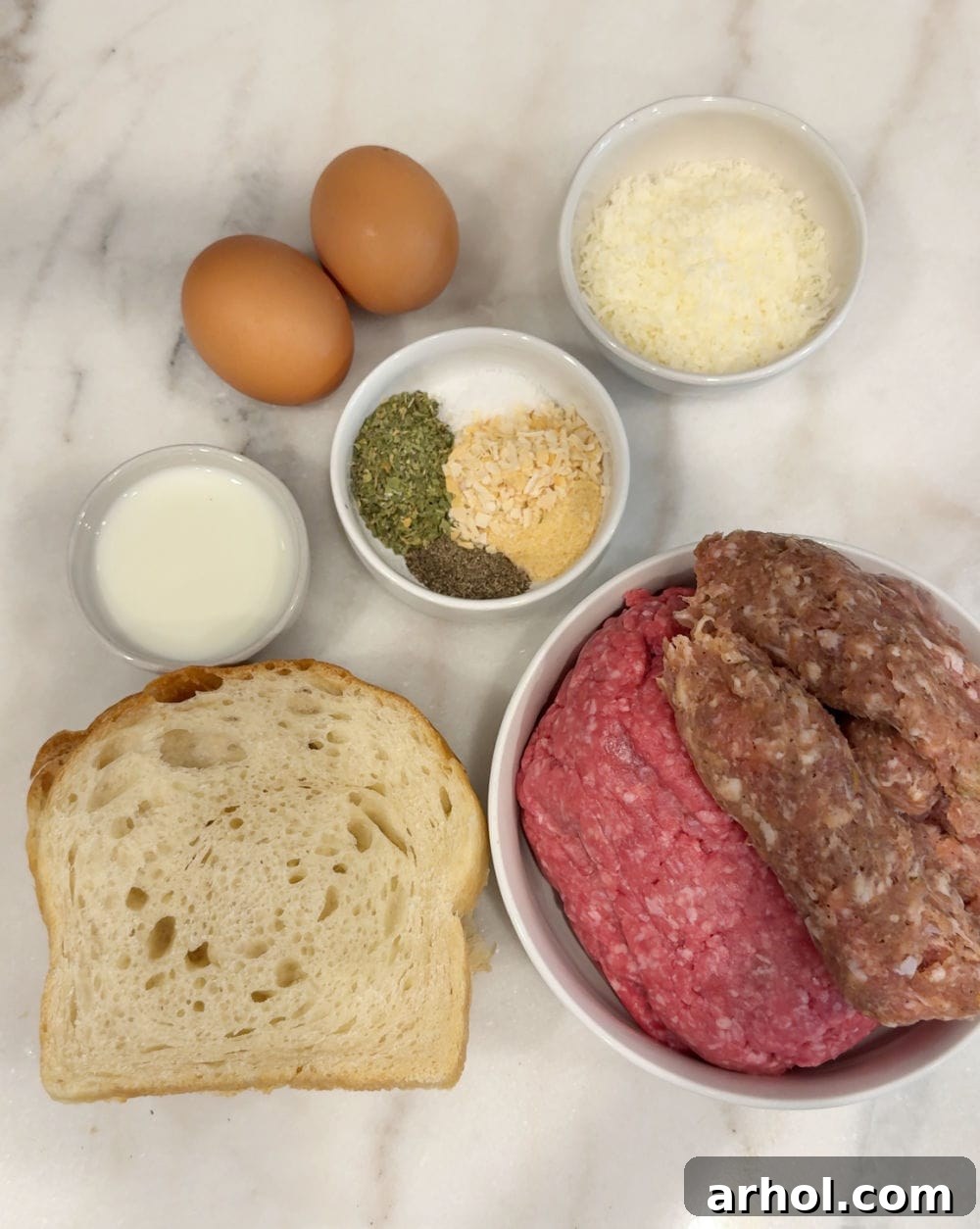 Key ingredients for homemade meatballs: ground beef, Italian sausage, sourdough bread, milk, eggs, various seasonings, and Parmesan cheese.