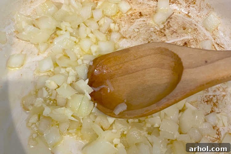 Sautéing chopped onions and garlic in olive oil in a Dutch oven, a key first step for homemade spaghetti sauce.