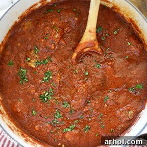 Homemade spaghetti sauce in a Dutch oven with fresh parsley garnish, ready to be served.