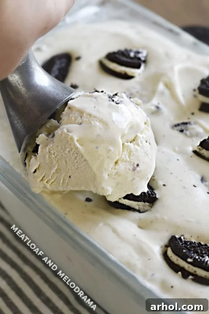 A scoop of creamy Oreo cookie ice cream being taken from a loaf pan.