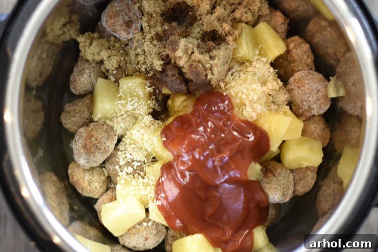 Frozen meatballs with pineapple chunks layered in the Instant Pot before cooking.