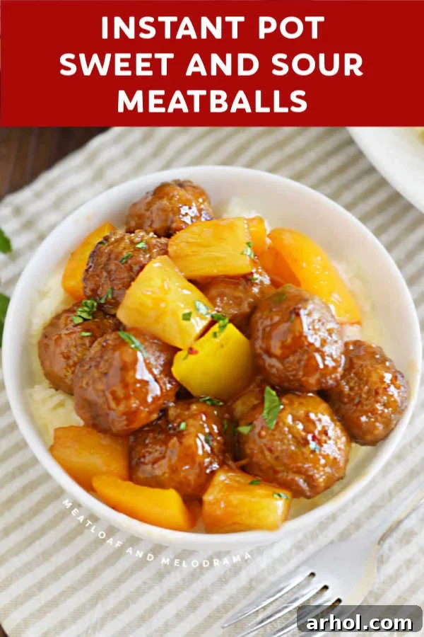 Close up view of sweet and sour meatballs in a white bowl, showing the glossy sauce and pineapple.