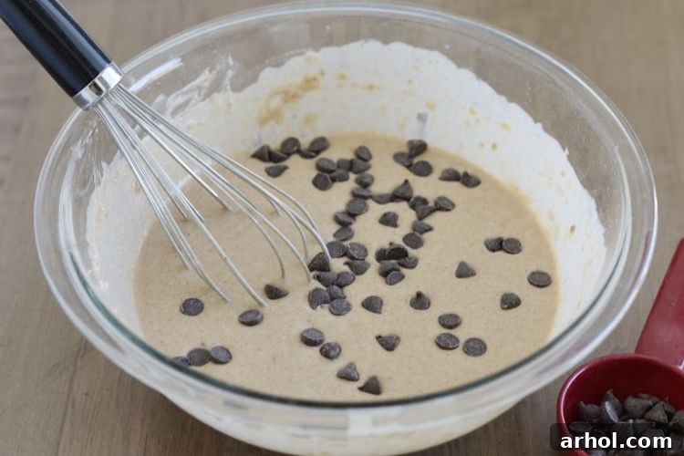 Gooey chocolate morsels stirred into the pancake batter, promising rich chocolatey bites.