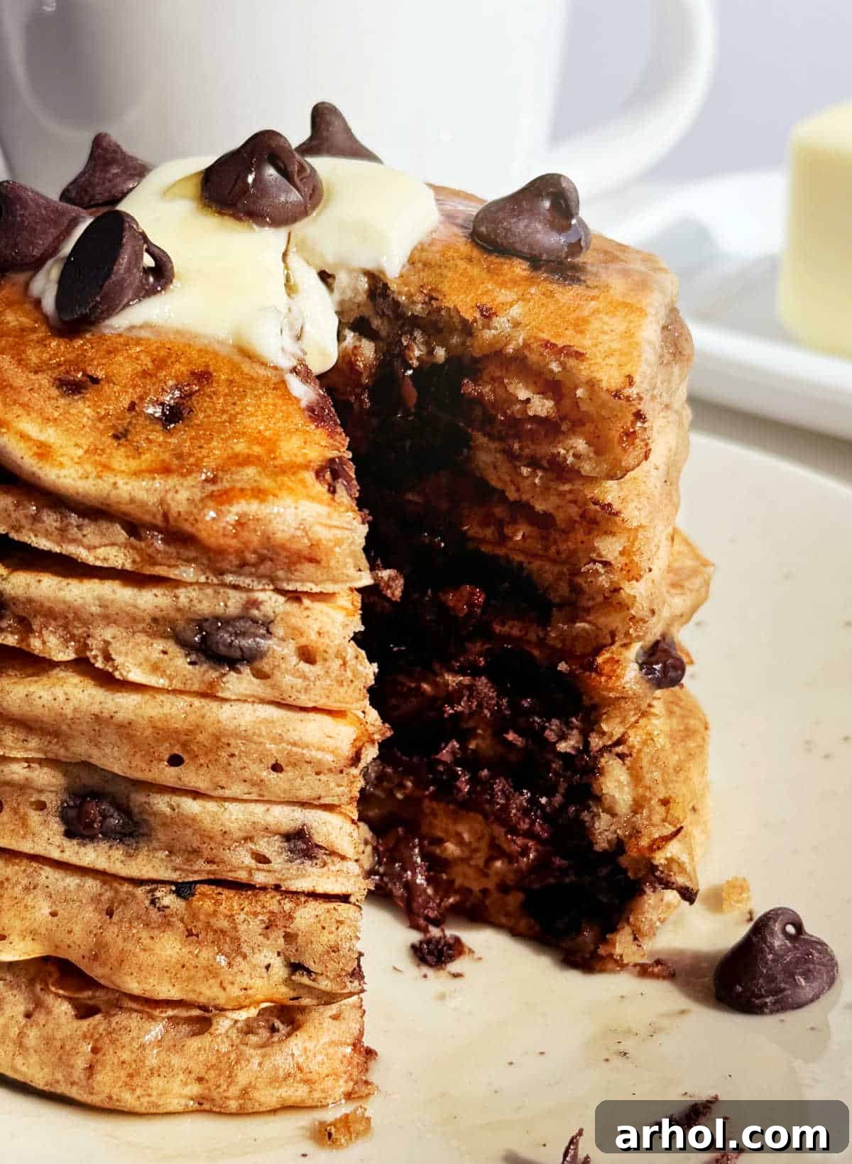 A stack of perfectly cooked chocolate chip pancakes, cut open to reveal the soft, fluffy interior and melted chocolate chips within.