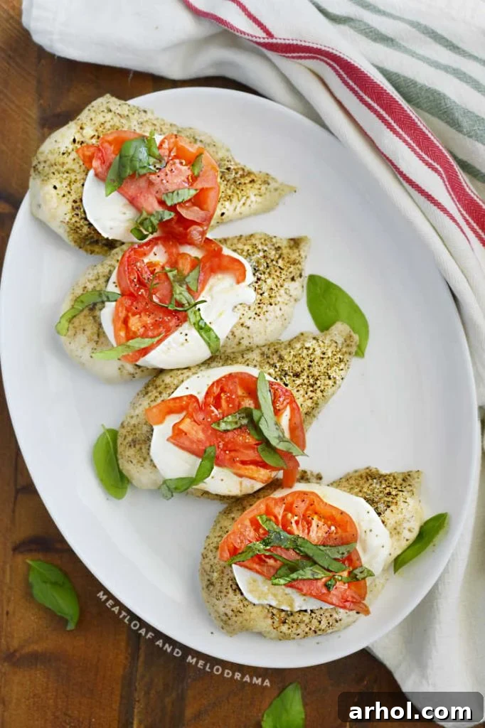Multiple servings of Caprese chicken breasts, garnished with fresh basil, on a large white platter, ready for a family meal.