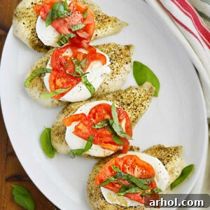 baked caprese chicken breasts with fresh mozzarella cheese, tomato slices and fresh basil leaves on a platter