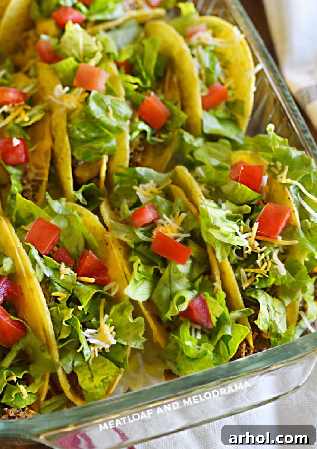 A baking dish filled with crispy ground beef baked tacos, ready to be customized with a variety of fresh taco toppings