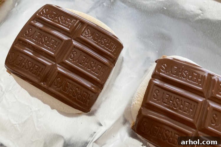 Melted milk chocolate squares draped over perfectly toasted marshmallows, creating a luscious layer on the graham crackers.