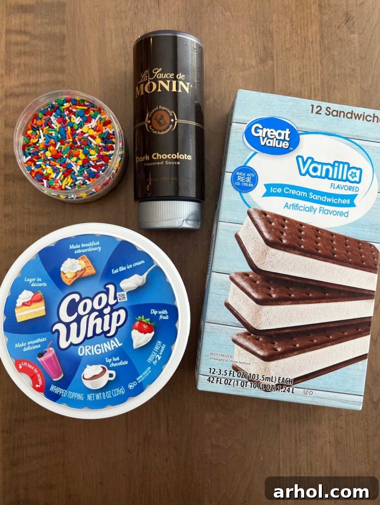Effortless Ice Cream Sandwich Cake 3 Ingredients for Ice Cream Sandwich Cake: a box of vanilla ice cream sandwiches, a tub of Cool Whip, chocolate syrup, and colorful sprinkles.