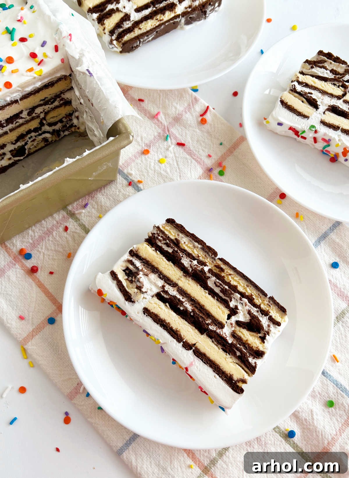 Effortless Ice Cream Sandwich Cake 8 Perfectly cut slices of Ice Cream Sandwich Cake served on white plates, showing distinct layers.
