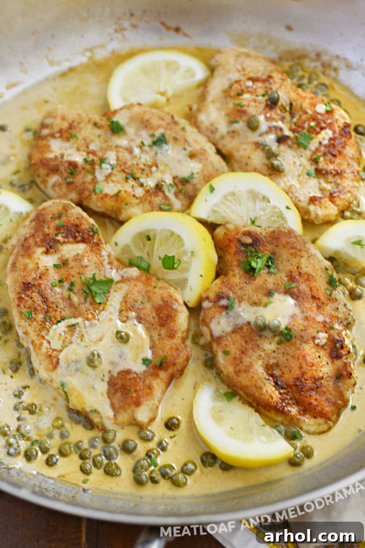 Chicken cutlets garnished with lemon slices and capers in a skillet, ready to be served.