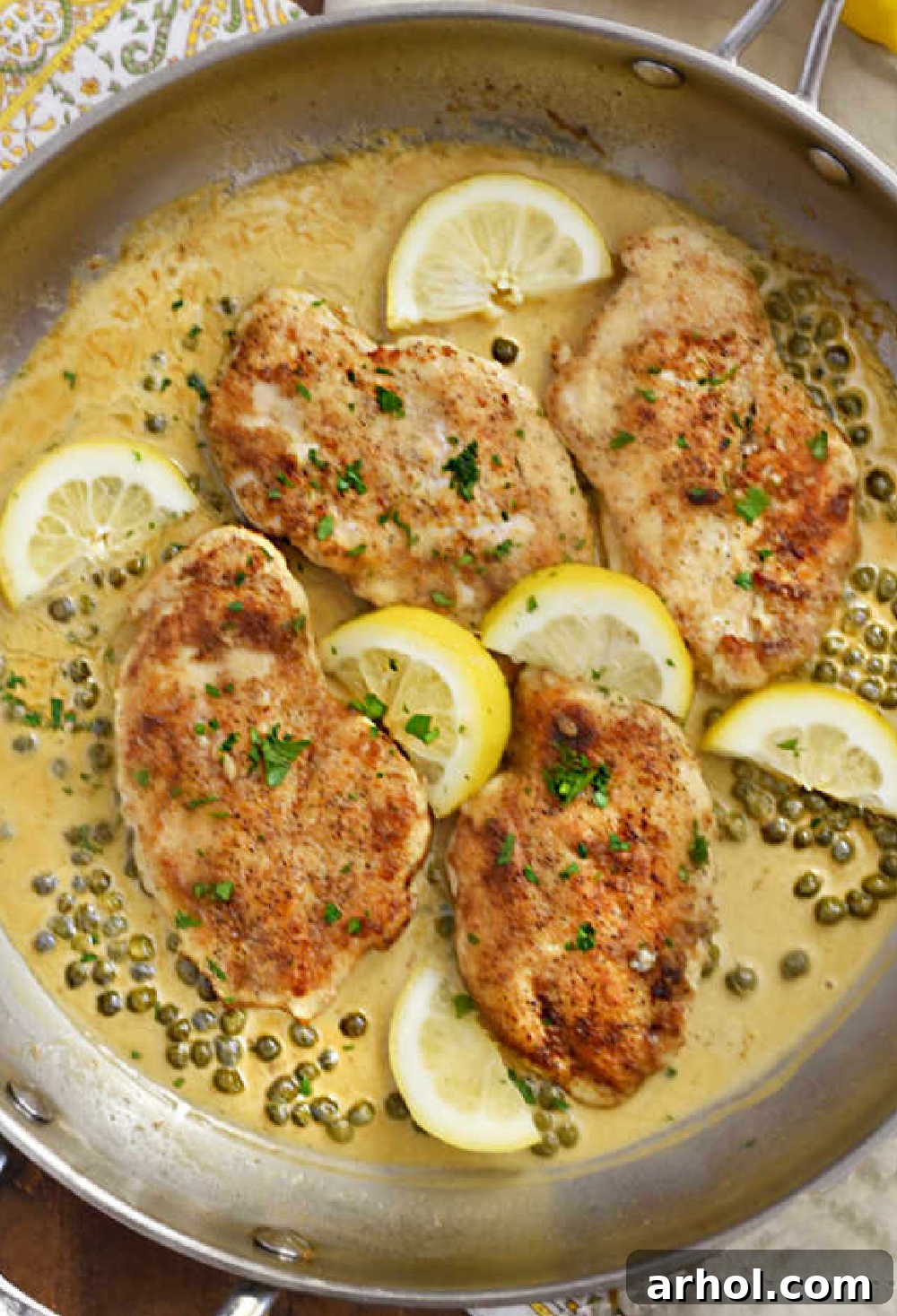 Lemon chicken piccata in a skillet, garnished with capers and lemon slices, ready for serving or storage.