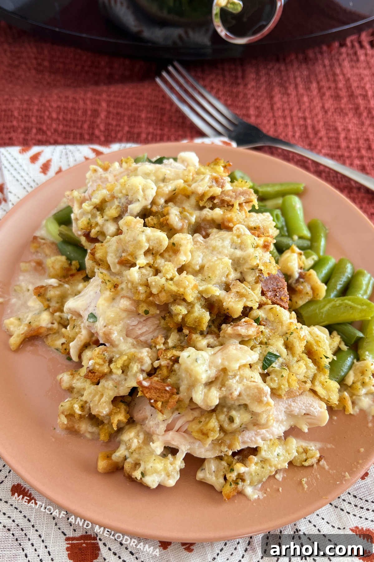 Delicious Crockpot Chicken and Stuffing served with green beans on a plate, with the slow cooker in the background