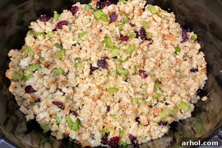Dry stuffing mix with optional dried cranberries and diced celery sprinkled over the creamy chicken in a crock pot
