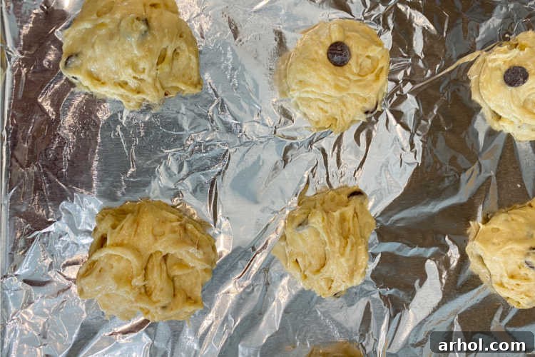 Unbaked banana chocolate chip cookie dough drops, neatly arranged on a parchment-lined baking tray, ready for the oven.