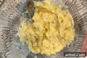 Mashed ripe bananas in a mixing bowl, ready for the next ingredient.