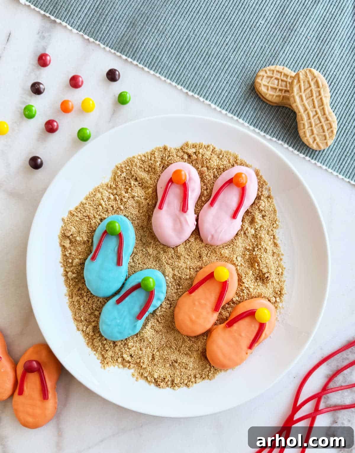 plate of flip flop cookies with on crushed graham crackers, resembling a beach scene.