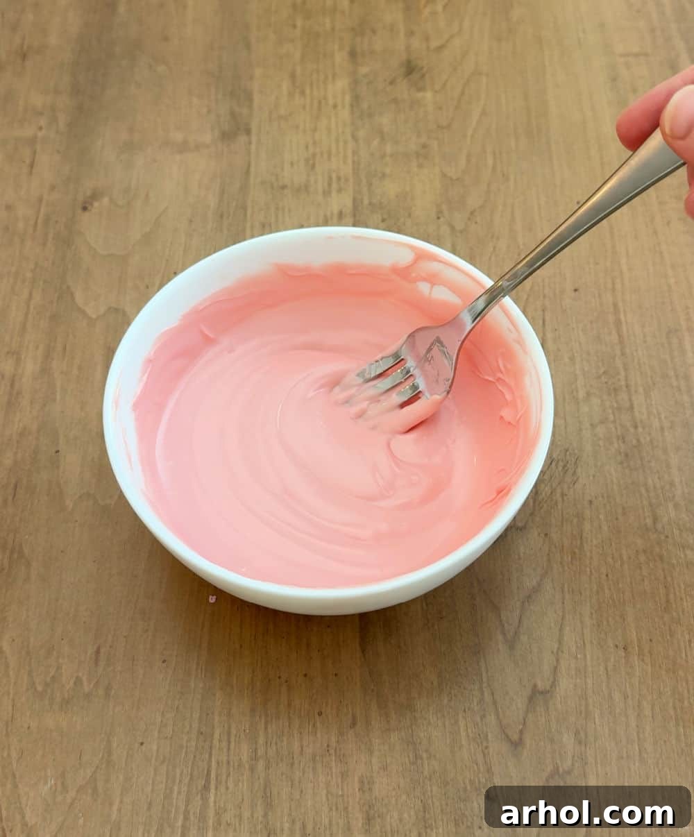 fork stirring melted candy coating in a bowl.