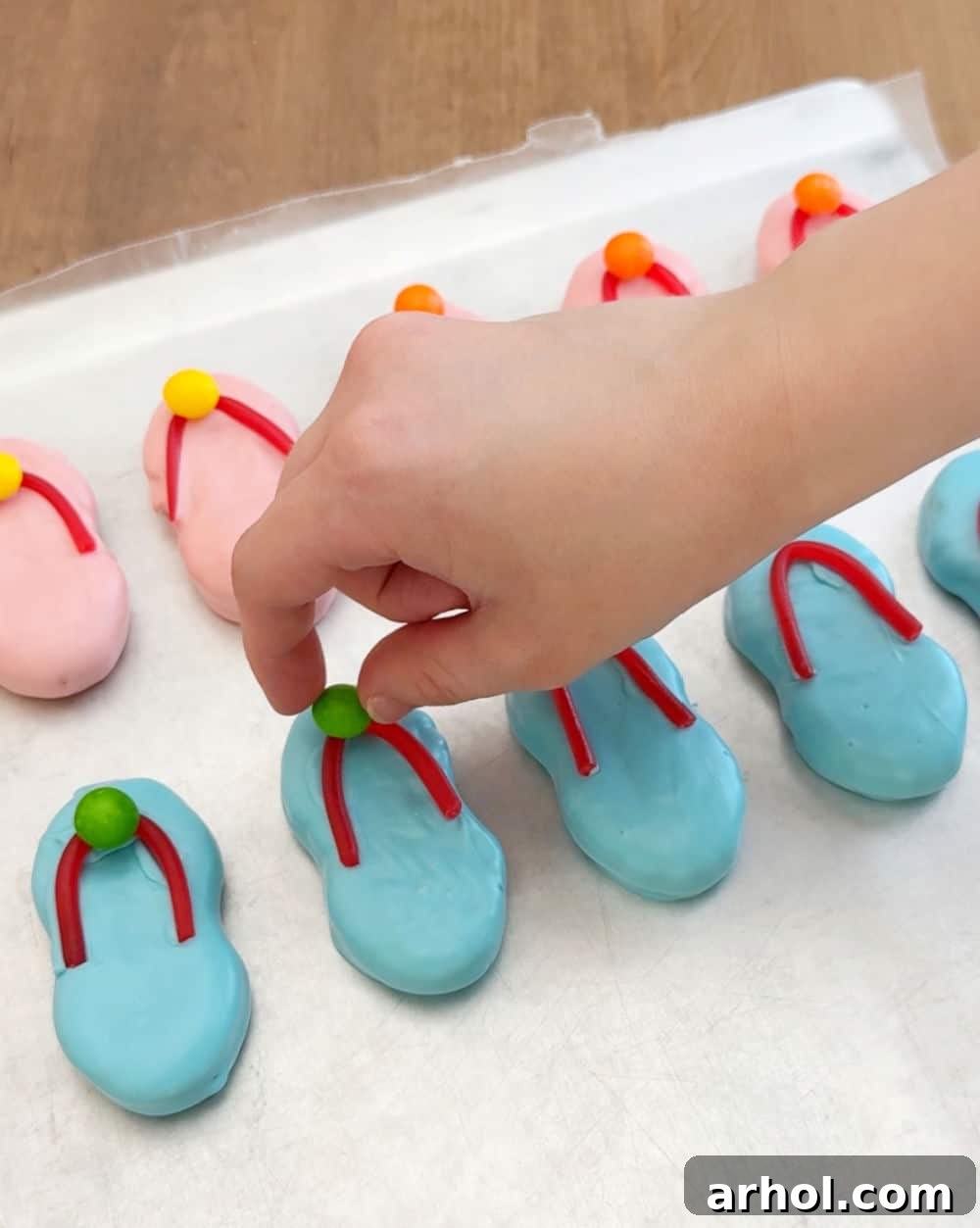 placing a Skittle on the center of the Twizzler strap on a flip flop cookie.