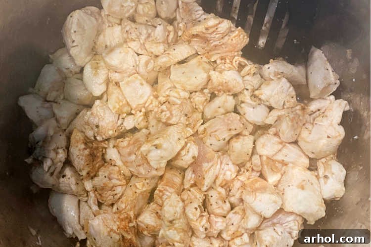 Creamy Instant Pot Chicken Spaghetti 3 Cubed chicken breast is being sautéed in an Instant Pot, showing the cooking process inside the appliance.