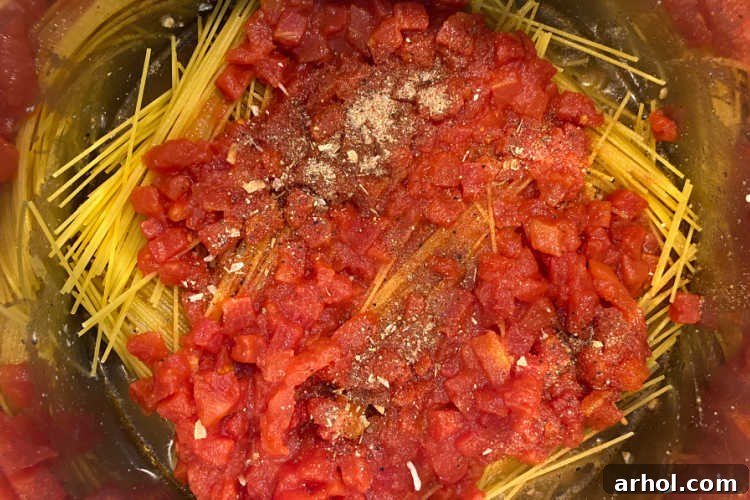 Creamy Instant Pot Chicken Spaghetti 5 Diced tomatoes are layered over spaghetti noodles in an Instant Pot, illustrating the 'no-stir' step before pressure cooking.