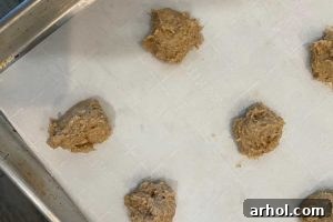Scoops of banana oatmeal cookie dough with chocolate chips on a baking sheet, arranged and ready to go into the oven