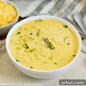 A bowl of Instant Pot Broccoli Cheddar Cheese Soup with a spoon, ready to eat, shown in a close-up.