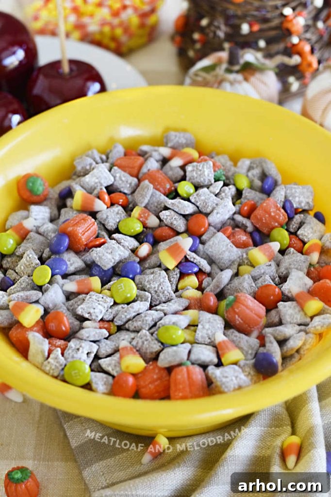 fall puppy chow muddy buddies in a yellow bowl with halloween candy