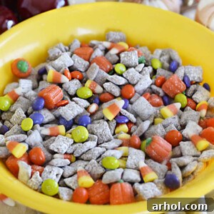 fall puppy chow muddy buddies in a yellow bowl with halloween candy