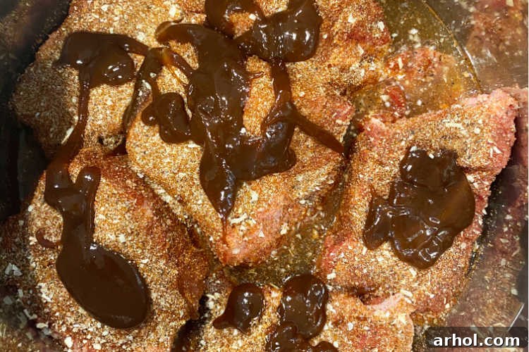 Chunks of beef chuck roast covered in barbecue sauce ready for pressure cooking in the Instant Pot.