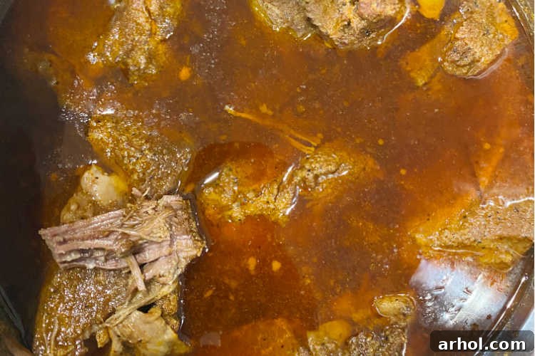 Cooked beef chuck roast simmering in its rich cooking liquid within the Instant Pot.