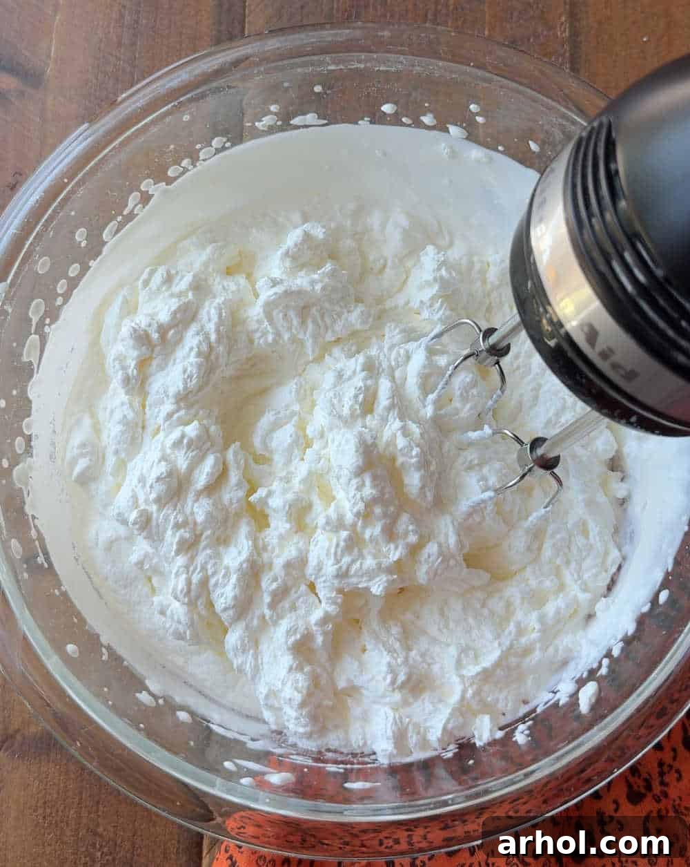 Electric mixer whipping heavy cream in a large bowl.