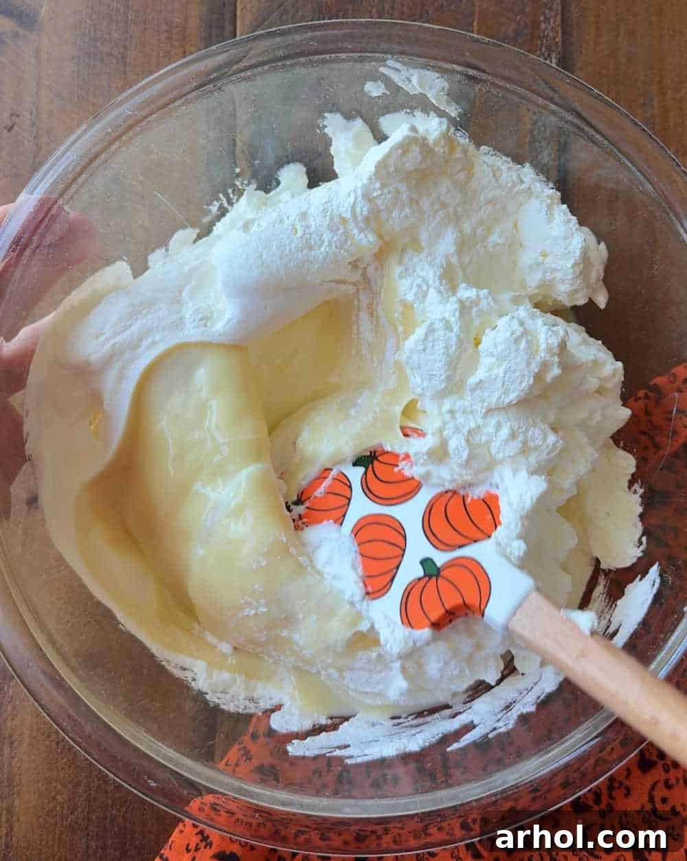 Gently folding whipped cream into sweetened condensed milk.