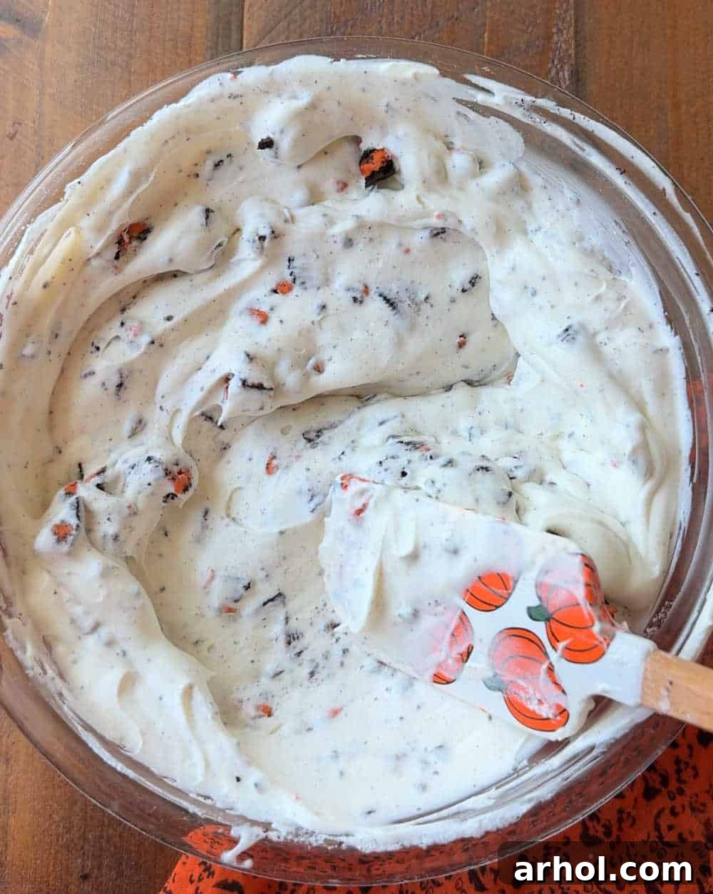 Stirring in crushed Oreo cookies into the ice cream base.