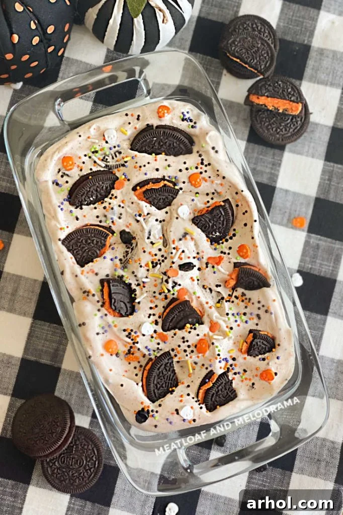 Cookies and Scream ice cream in a bowl on a table with Halloween Oreos and small decorative pumpkins.