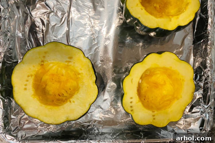 Cut open, baked acorn squash halves on a baking sheet, ready for stuffing