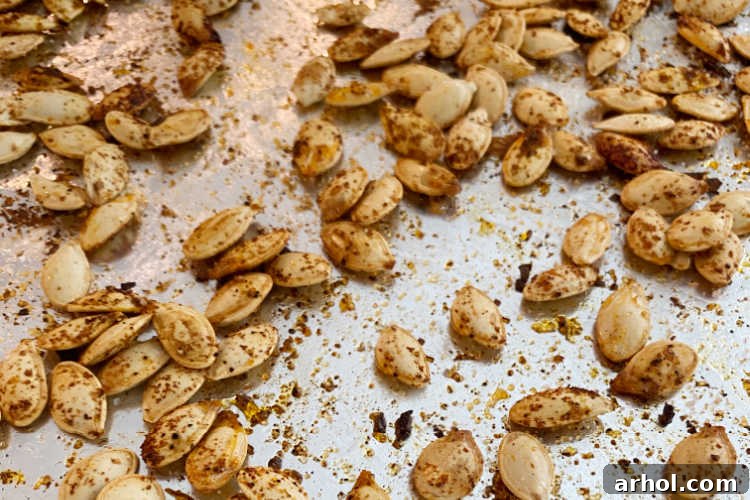 Freshly baked seasoned pumpkin seeds cooling on a cookie sheet, golden brown and crisp.