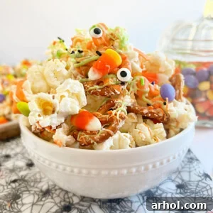 A bowl of Monster Munch Halloween popcorn mix with pretzels, candy eyes, and various Halloween candies.