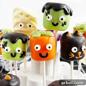 Halloween marshmallow pops decorated as cute monsters and ghosts, displayed in a cake pop holder.
