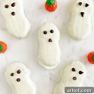 Nutter Butter ghost cookies arranged with candy pumpkins on a marble surface, perfect for Halloween.