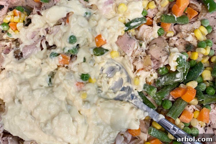 Creamy chicken, soup, and mixed vegetables blended in a baking dish, ready for the next layer.