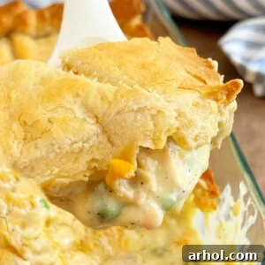 A scoop of chicken pot pie casserole with crescent roll crust on a serving spoon.