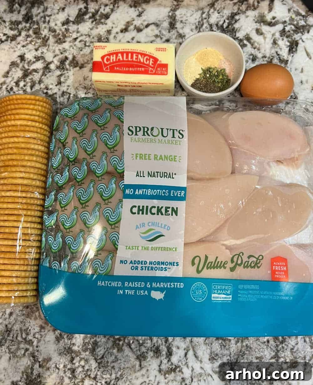 Fresh ingredients laid out for Ritz Cracker Chicken: chicken breasts, Ritz crackers, butter, egg, and various seasonings.
