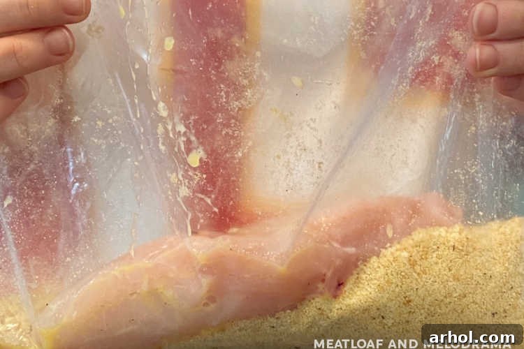 Chicken breast being coated in buttery Ritz cracker crumbs inside a freezer bag for an even, crispy crust.