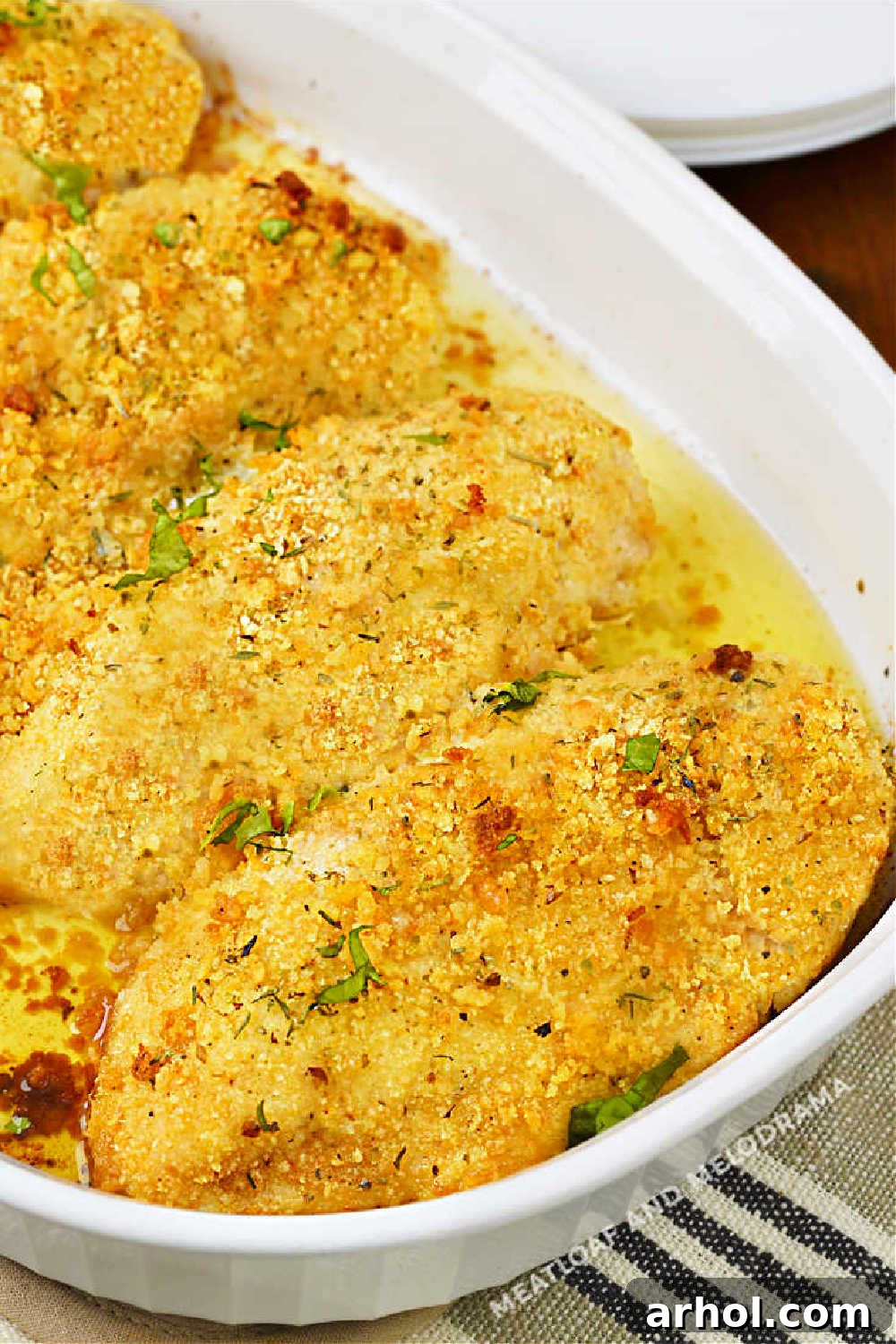 Multiple pieces of baked Ritz Cracker Chicken with melted butter pooling in the baking dish, creating a savory sauce.