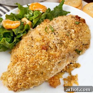ritz cracker baked chicken breast on a white plate with salad