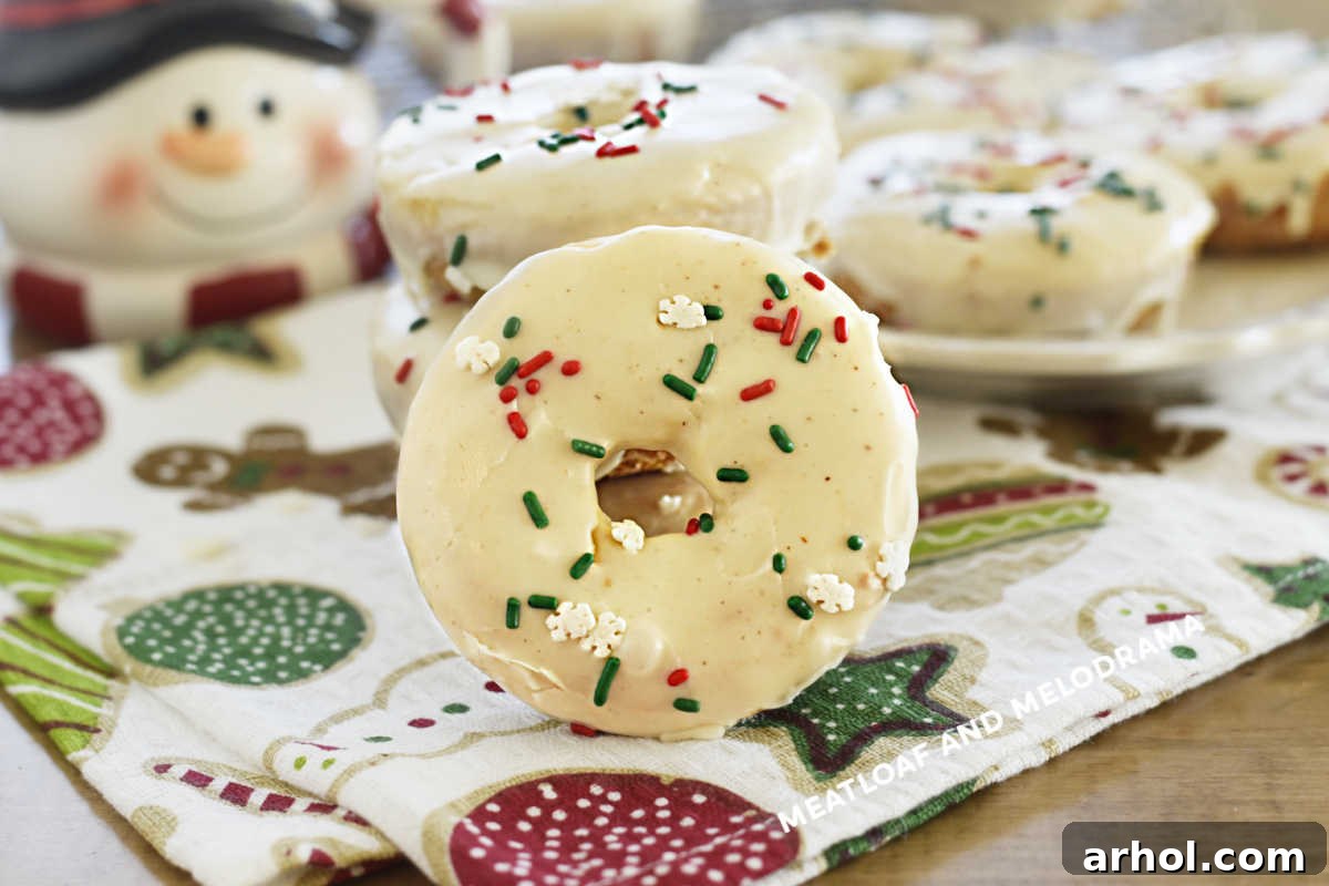 Festive Baked Eggnog Donuts 8 A festive spread of baked eggnog donuts with sweet glaze and colorful red and green sprinkles, invitingly arranged on a table for a holiday celebration.