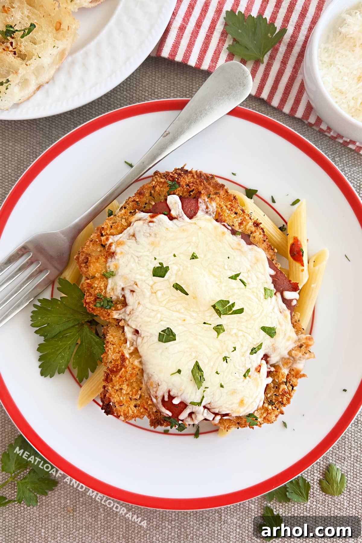 Golden-brown panko-coated baked chicken Parmesan with melted mozzarella cheese over penne pasta, garnished with fresh basil.